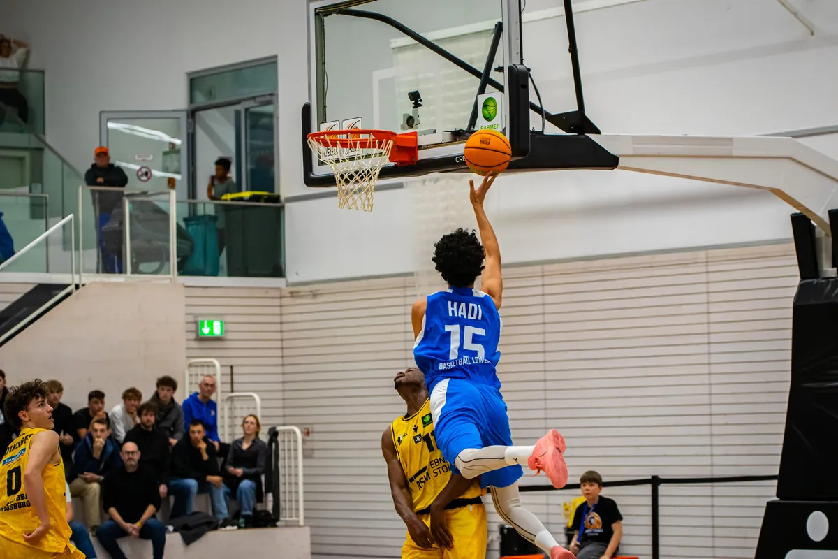 Löwen-Spieler beim Dunk am Korb vor den Zuschauerrängen