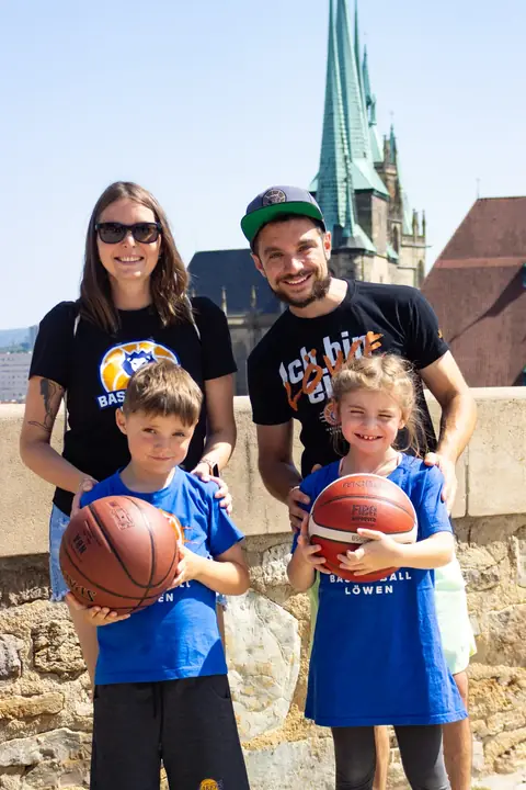 Eltern und zwei Kinder mit Basketbällen vor der Festungsmauer