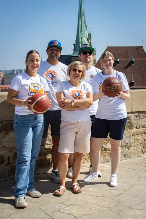 Vier Fans in weißen Shirts mit Basketbällen in den Armen