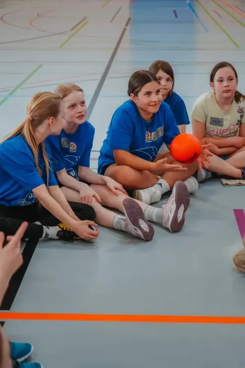 Teilnehmerinnen sitzen mit Ball beim QUNDIS Girlscamp 2026