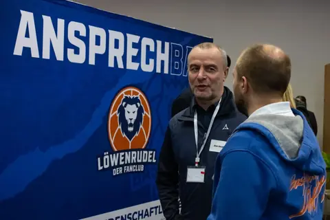 Gespräch vor dem AnsprechBar-Banner des Fanclubs