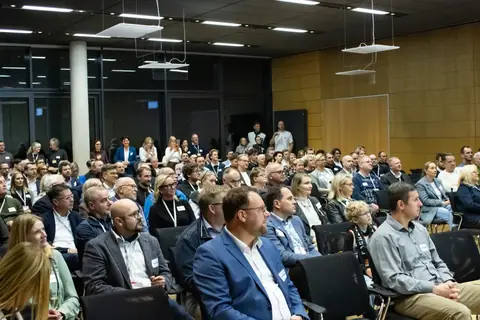 Gäste verfolgen den Vortrag im Saal